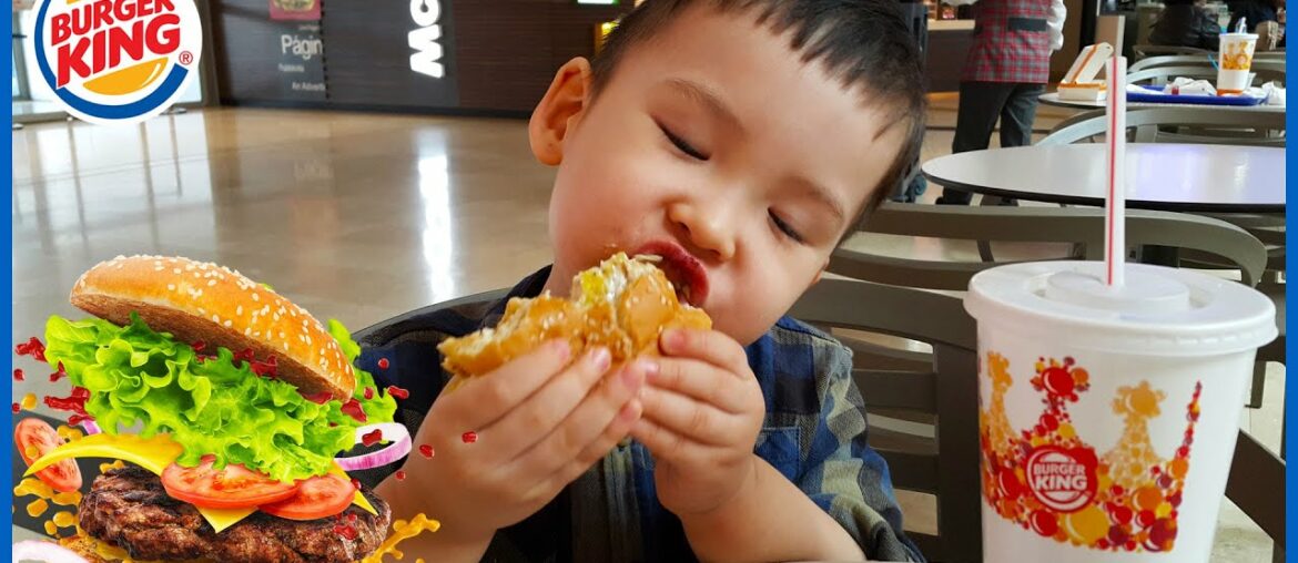 A child biting a burger. Ready to eat. Toddler kid looking at a big burger. Eating Sounds.