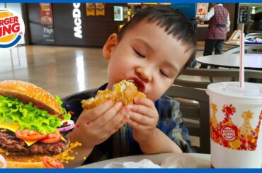 A child biting a burger. Ready to eat. Toddler kid looking at a big burger. Eating Sounds.