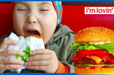 Hungry kid. Little cute baby at Burger King restaurant in Istanbul. Asian baby boy eating hamburger.