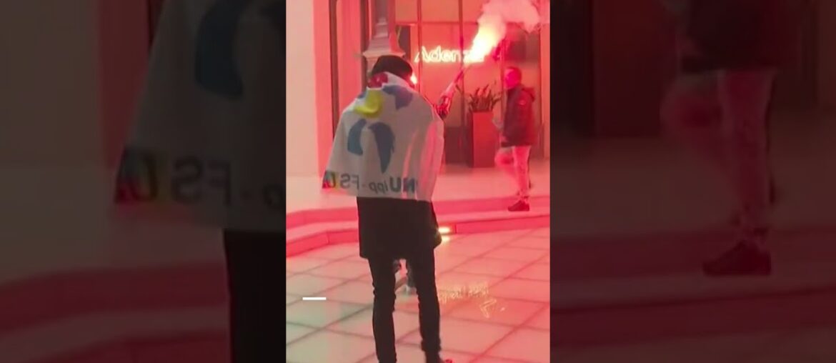 French protesters light flares while storming investment firm