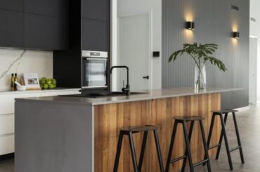 Black backdrop cabinets framed by a waterfall countertop over a reclaimed wood island. Studio Black Interiors, Australia