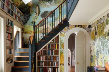 Staircase surrounded with built-in bookshelves and vibrant wallpapers in a 1930s country house, South Downs, southeastern England [3713x5000]