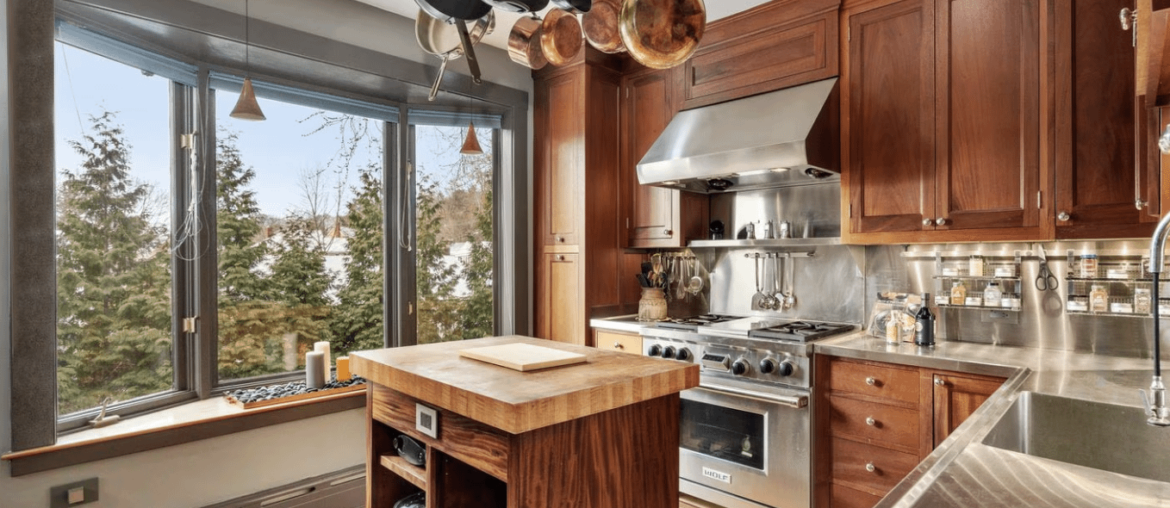 Belmont, MA kitchen features recessed lighting, a bay window, an island with a butcher-block top, and a pot rack [1358 x 886]
