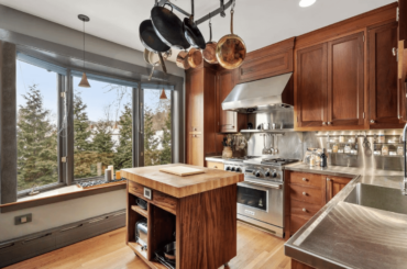 Belmont, MA kitchen features recessed lighting, a bay window, an island with a butcher-block top, and a pot rack [1358 x 886]