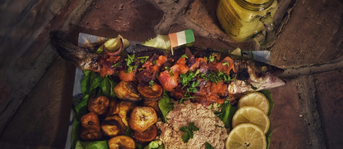 Bar braisé, Allocos (frites de bananes plantains) et Attiéké (semoule de manioc) avec du jus de gingembre.