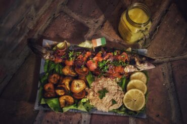 Bar braisé, Allocos (frites de bananes plantains) et Attiéké (semoule de manioc) avec du jus de gingembre.