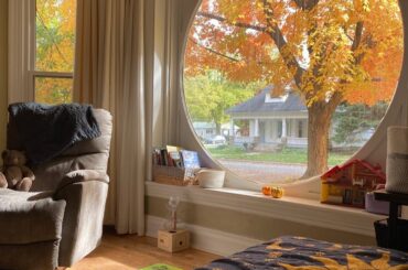 Room with autumn views through a round window in a renovated Midwest Victorian home [1124x1406]