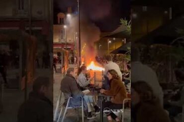 French diners enjoy wine as fire lit by protesters burns nearby