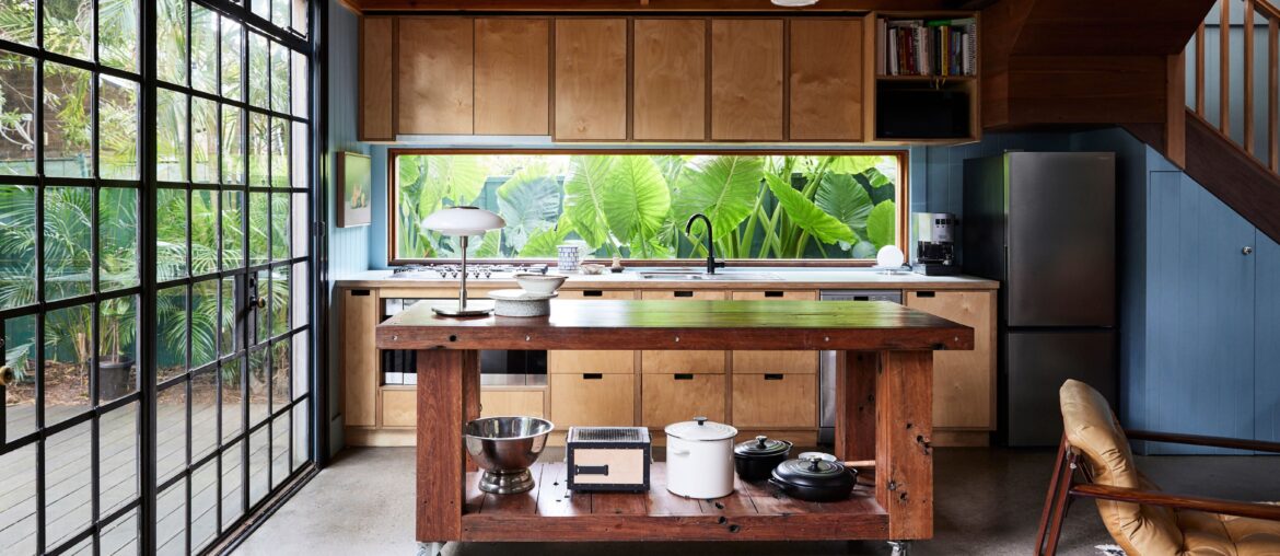 Kitchen and dining space with black framed windows with views of tropical foliage in an eclectic home, St Peters, Inner West of Sydney, Australia [6250x3515]