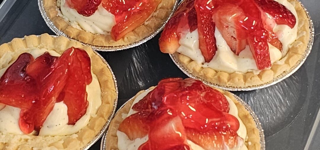 Strawberry tartlets with homemade vanilla cream in shortcrust pastry cases coated with melted white chocolate, with strawberry topping cake glaze