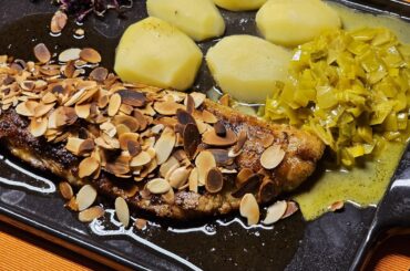 Fried fillet of pike-perch with roasted almonds in a lemon-butter sauce, with leek in a curry-white wine sauce, boiled potatoes and red radish sprouts