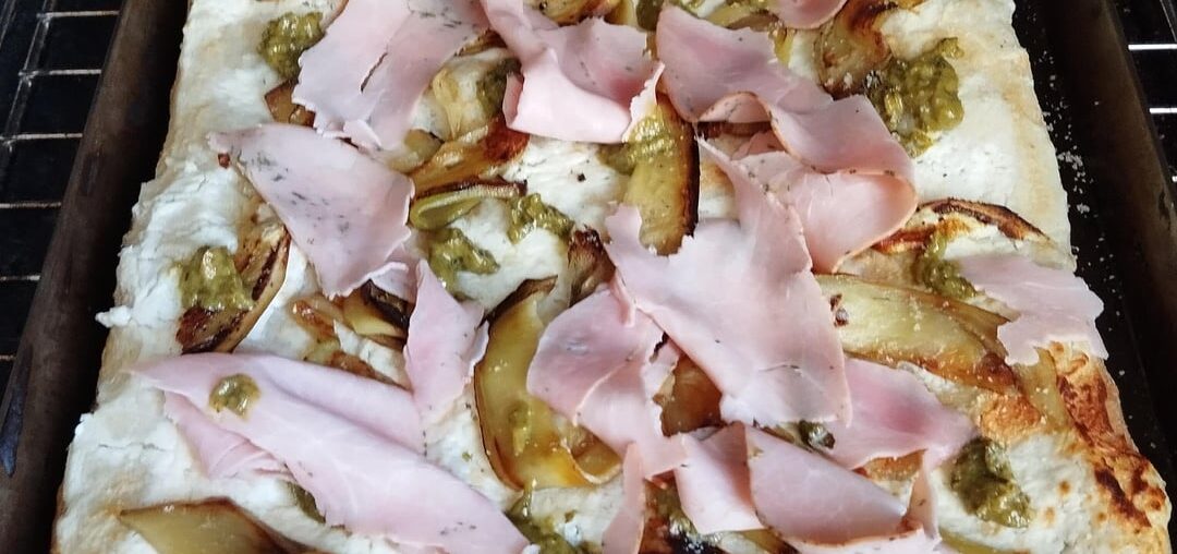 Pinsa Romana. Base crème ricotta pecorino. Aubergine grillées, pesto citron, pointe de poudre d'amande, prosciutto cotto aux herbes.