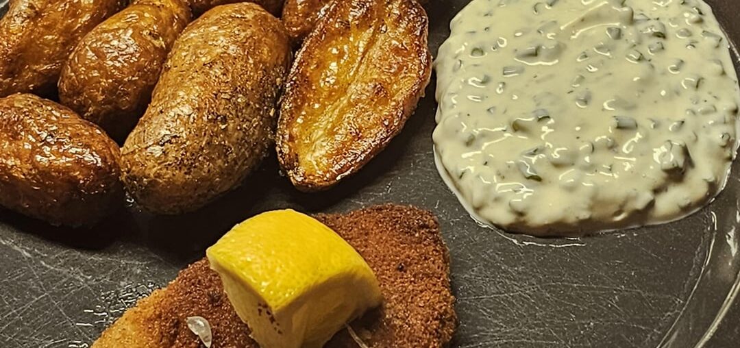 Schnitzel, accompanied by fried potatoes and a homemade chive-based sourcream sauce as a dip with the potatoes