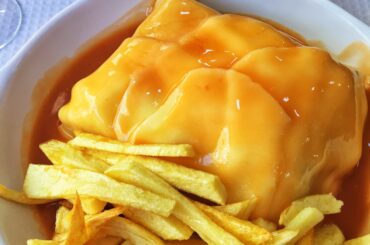 Francesinha (Portugal) - technically a sandwich, with all kinds of deli meats, covered in cheese, an egg and accompanied by fries/crisps and hot sauce!