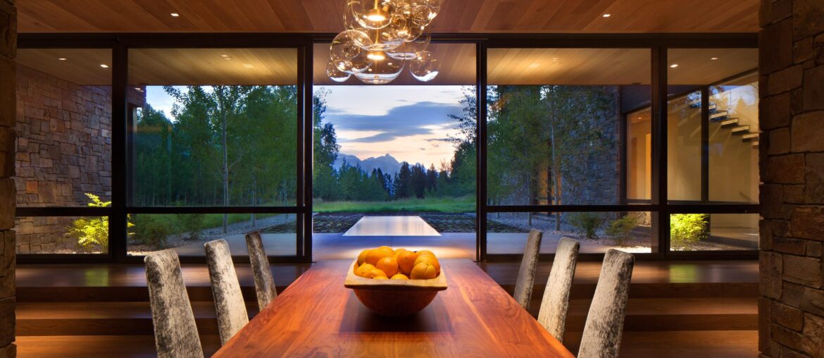 Sliding glass doors separate the dining area from a reflecting pool and the Wyoming wilderness | Wilson, WY [2364 x 1576]