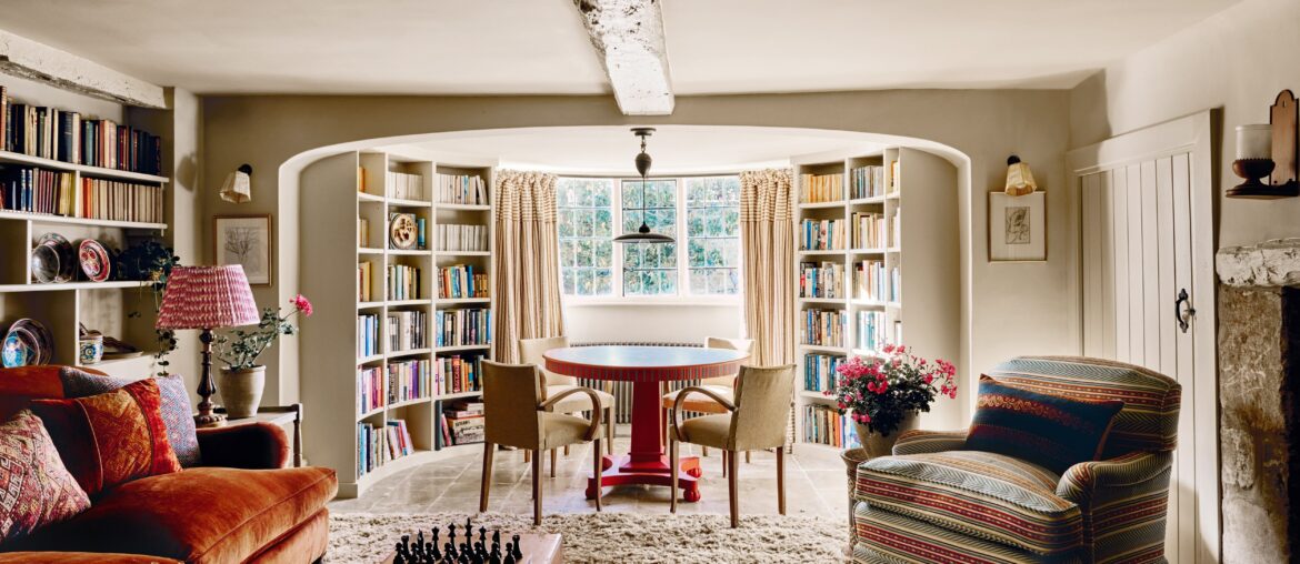 Games room with a curved window alcove and bespoke bookcases in a 17th-century Cotswolds house with later additions, England [5000x3334]