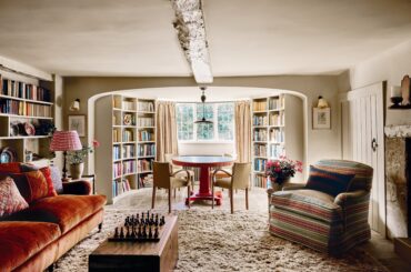 Games room with a curved window alcove and bespoke bookcases in a 17th-century Cotswolds house with later additions, England [5000x3334]