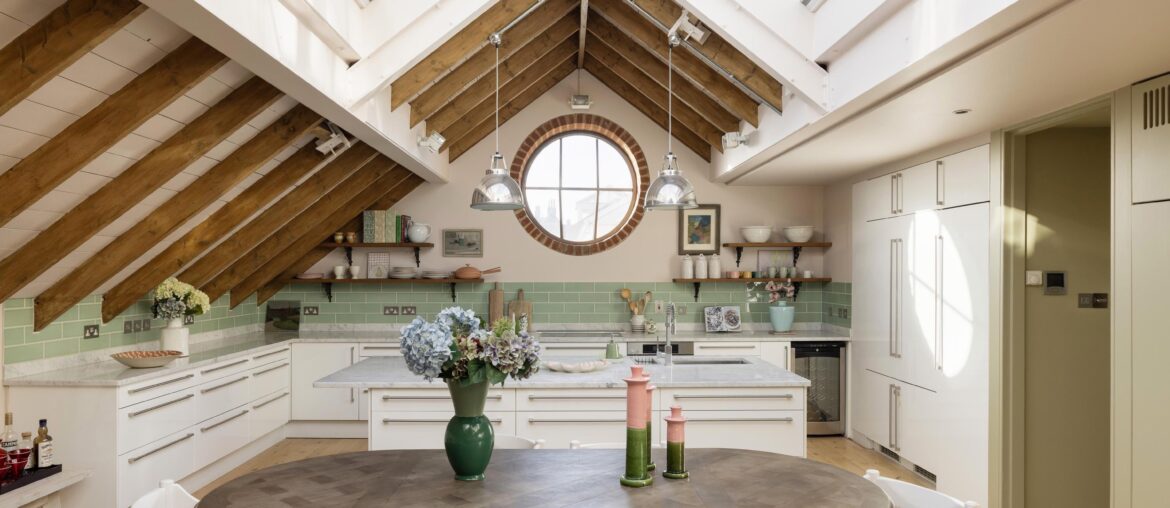 Marble countertop and teal tiled kitchen with a porthole window in a renovated three-bedroom duplex in a former Victorian dairy, North Kensington, west London, UK [2999x2000]