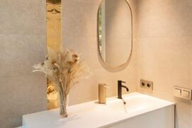 Modern bathroom with grey stone walls, a tall gold stripe, and a white sink, Barcelona Spain [640x960]