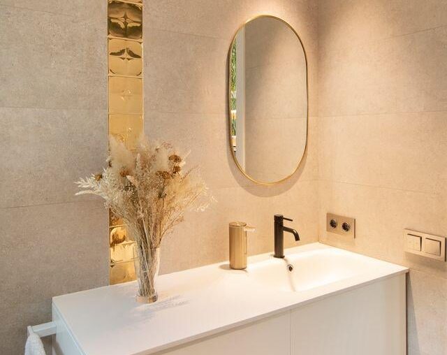 Modern bathroom with grey stone walls, a tall gold stripe, and a white sink, Barcelona Spain [640x960]