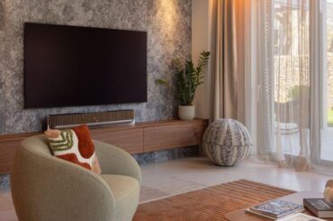 Living room with textured stone accent wall, floating walnut console and warm ambient lighting [1080x1350]