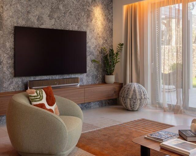 Living room with textured stone accent wall, floating walnut console and warm ambient lighting [1080x1350]