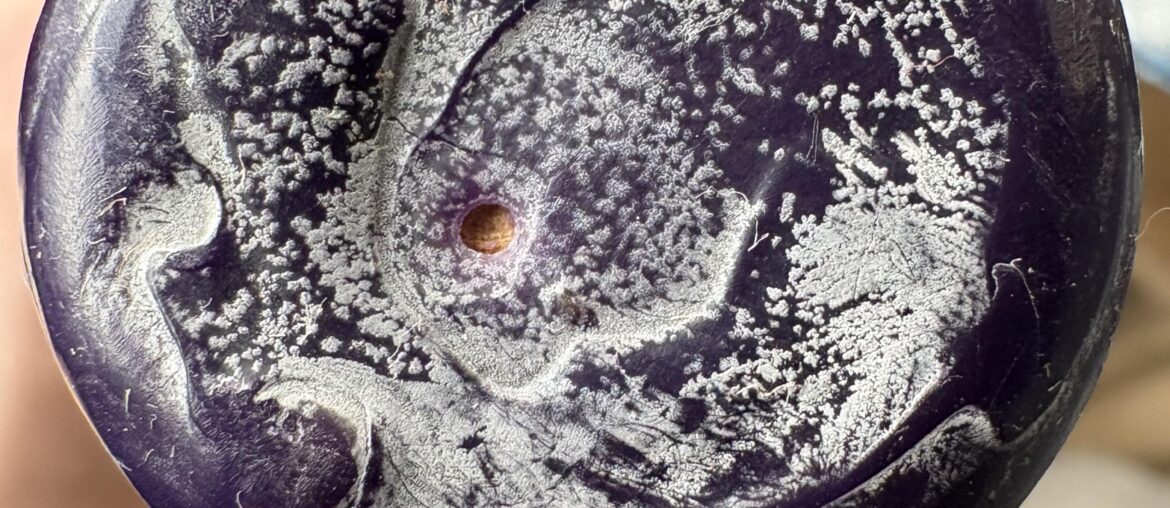 Second hand bottle has (needle?) hole in the wax